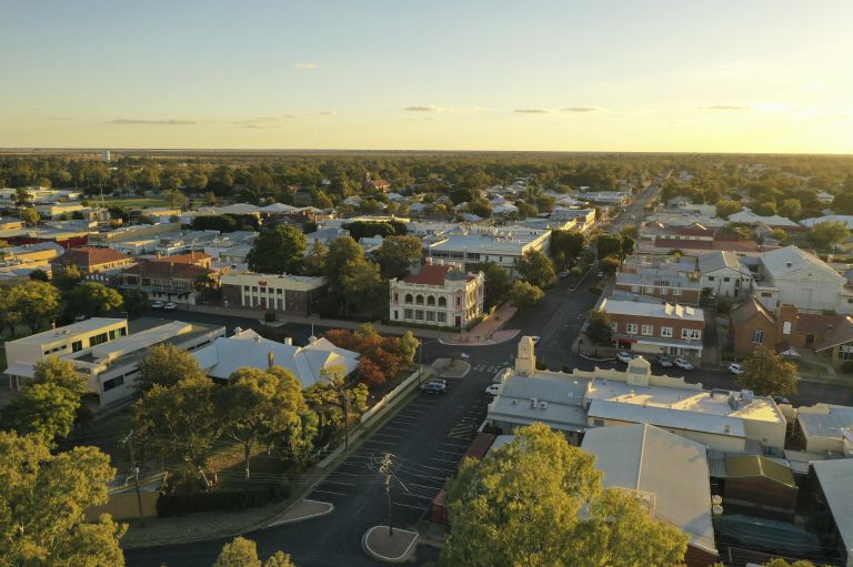 an overhead view of Moree, a town in regional NSW. There are two roads crossing in the middle and the buildings are surrounded by trees. The sky is mostly clear and the sun is low in the sky