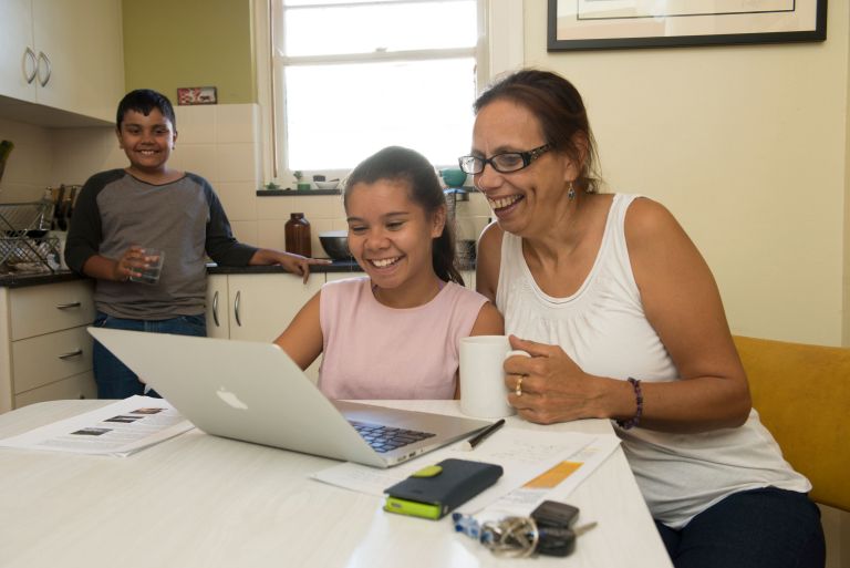 Aboriginal family looking at computer in kitchen