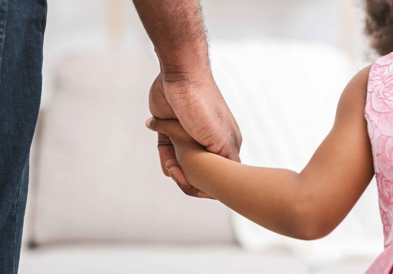 Male adult holding a young child's hand 