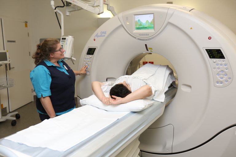 Radiographer with patient and CT scanner