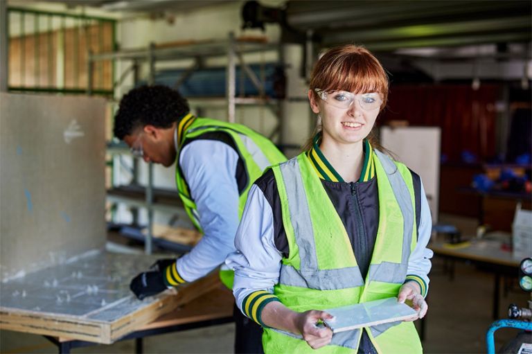 Female apprentice with supervisor cutting tiles