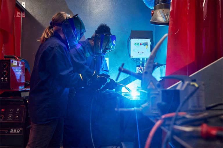 Supervisor watching apprentice welding