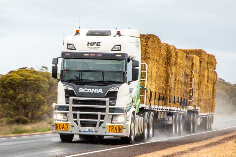 Lorry stacked with fodder on a rainy day moving along a main road