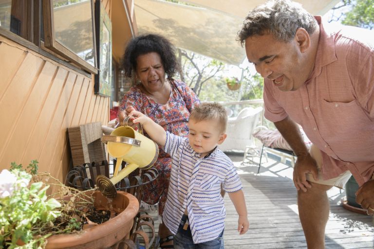 Small boy waters plants with his grandmother and grandfather 