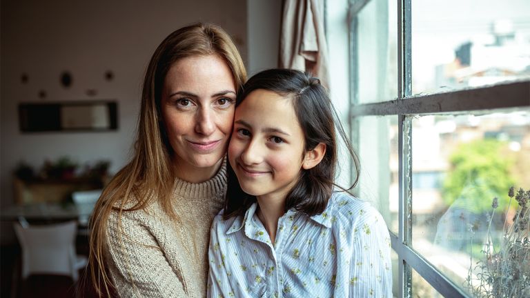 A woman and child sitting close to each other, smiling.