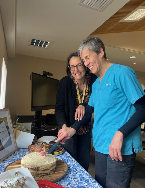 Dietitians Paula Cauduro and Margarita Contis stand side-by-side cutting a cake.