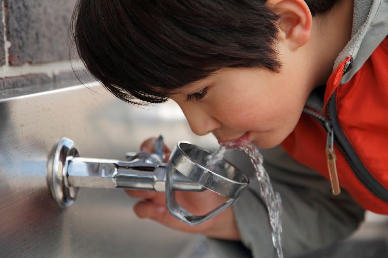 A child drinking water from a bubbler