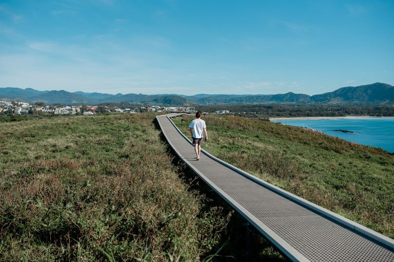 A person walking on the Coffs Harbour Marina Walk.