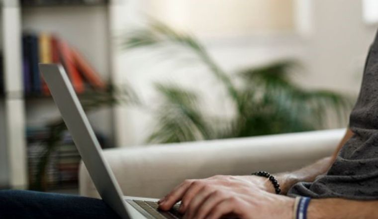 A man sitting on his couch using a laptop