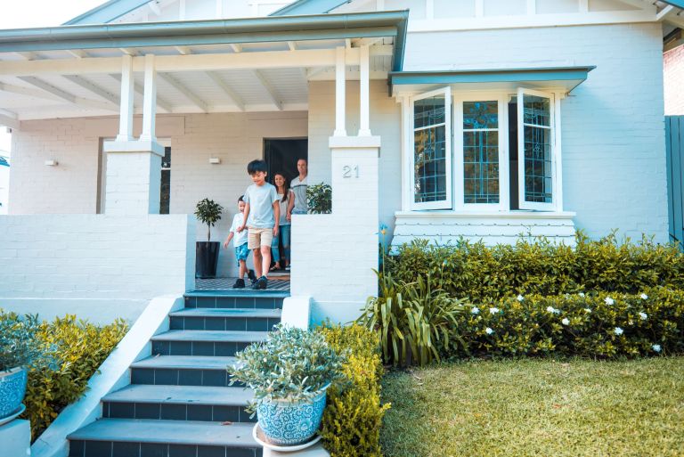 A family walks down the steps of a painted brick house.