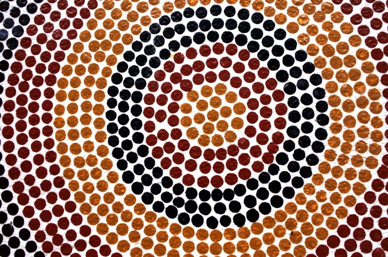 First Nations artwork showing red, orange and black dots in a ripple pattern.