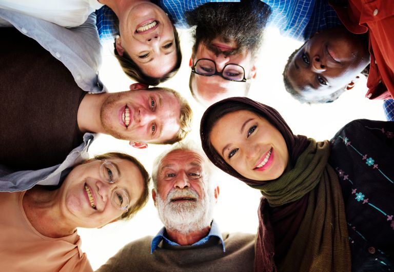 A group of people smiling and looking down at the camera from diverse backgrounds.