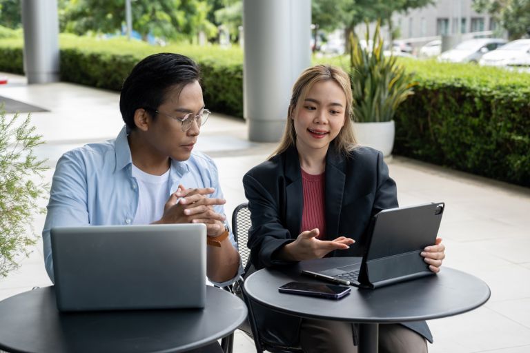 Two people dressed in corporate clothing, lookings at tablet screens.