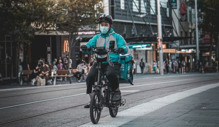 A male gig worker riding a delivery bike in the Sydney CBD