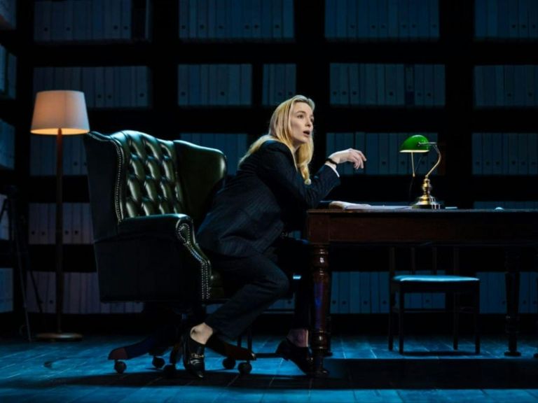 woman on stage sitting behind desk