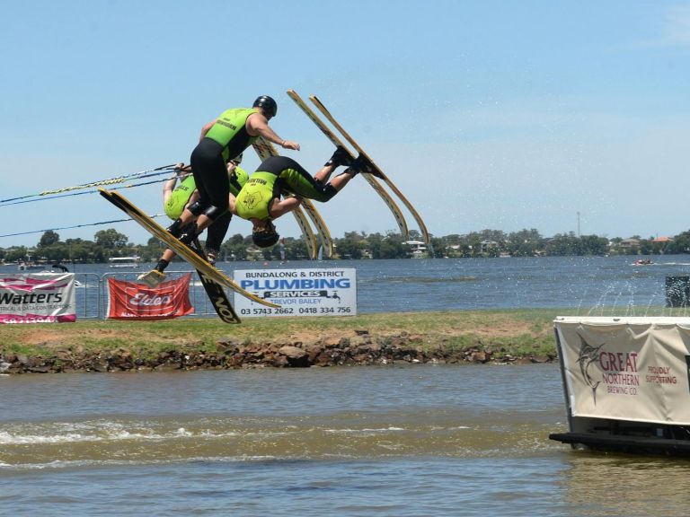 Three water skiiers going over the jump.