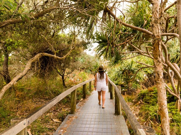 Lady walking down path in between coastal trees