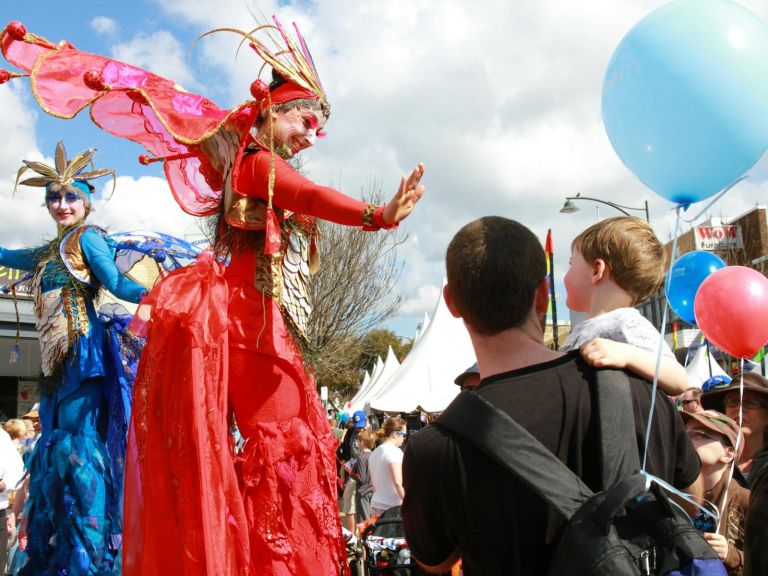 Festival entertainers on stilts with dad and child