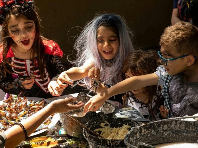 Kids sitting around a table with treats dressed in Halloween costumes