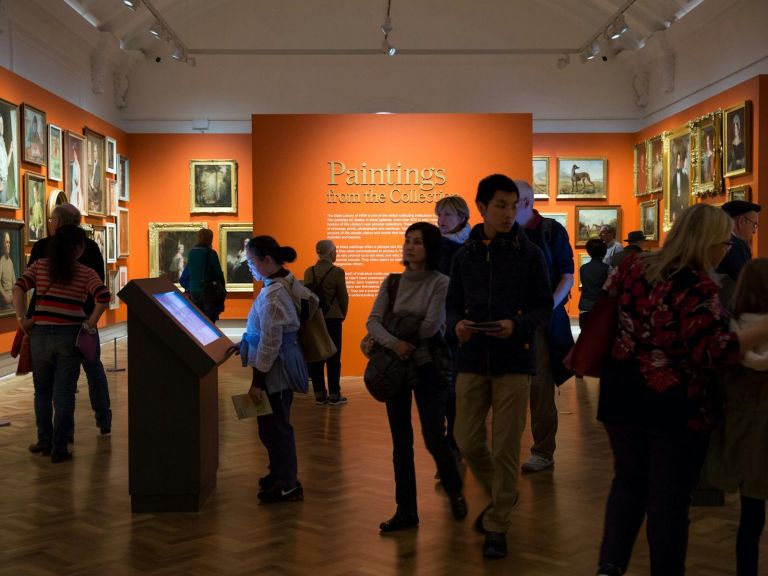 Crowd of people mingling and enjoying art in a gallery space