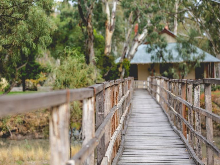 Wooden walkway leading to old building, trees surrounding