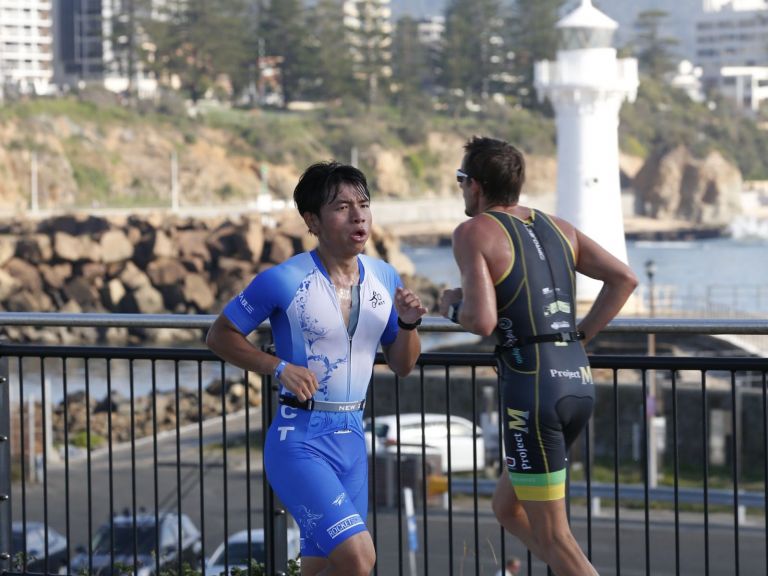 Two runners on the course, lighthouse in the background