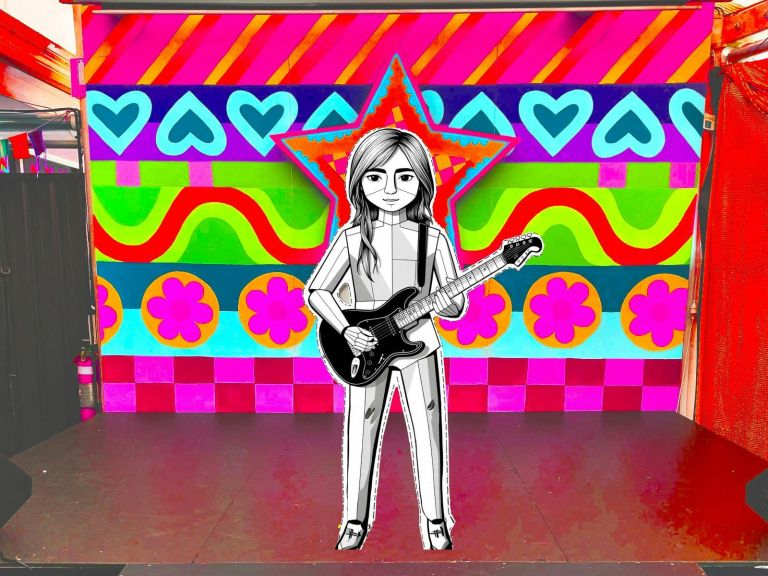 Cardboard cutout holding a guitar in front of a psychadelic background on a stage