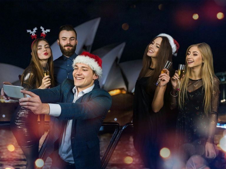 Guests clicking selfie with the iconic Opera House in the background on a Magistic xmas party cruise