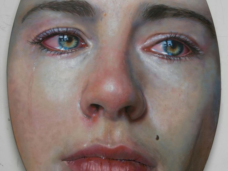 An highly detailed image of a woman's face crying in hyper realism on an oval canvas.