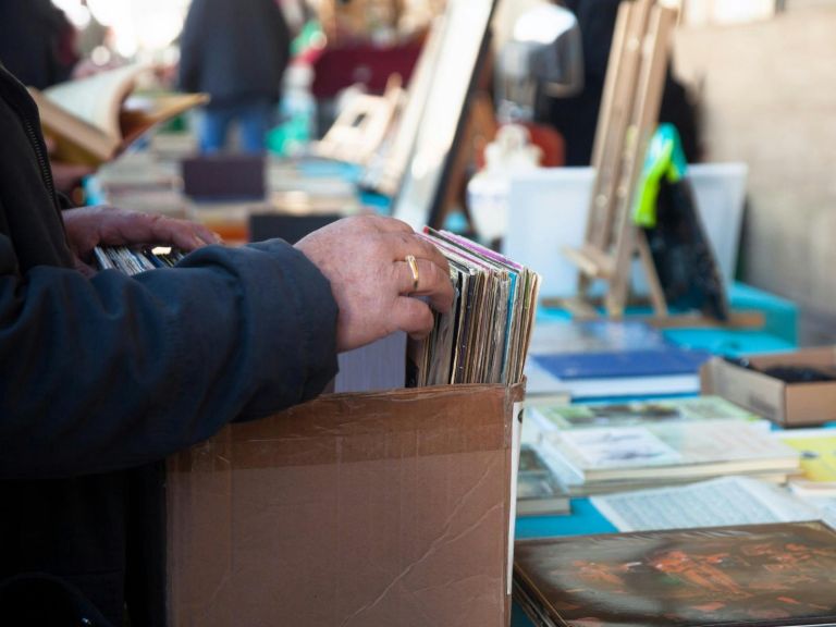 Person's hands browsing through a bric-a-brac stall