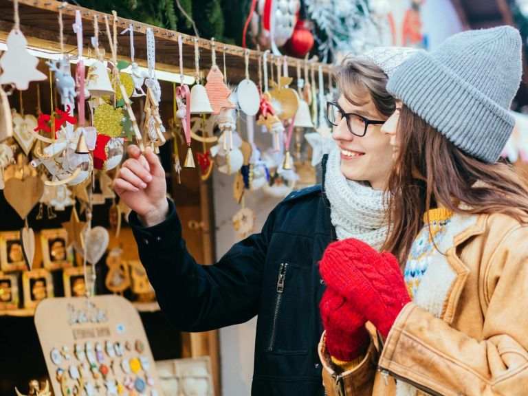 A couple shopping at a Christmas market stall.