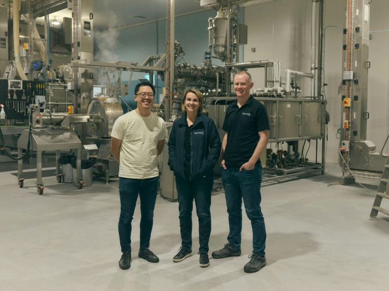 Two men and a woman standing in an industrial food production space