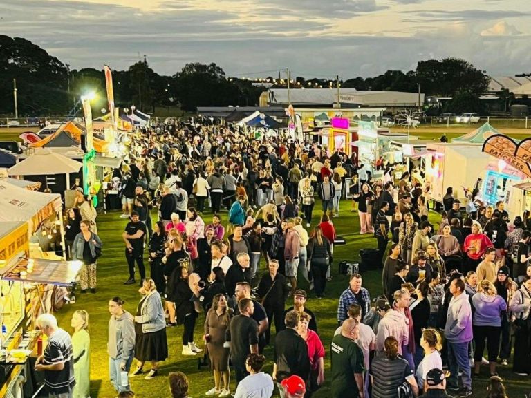 Crowd of people  round a line of Street food vendors at sunset