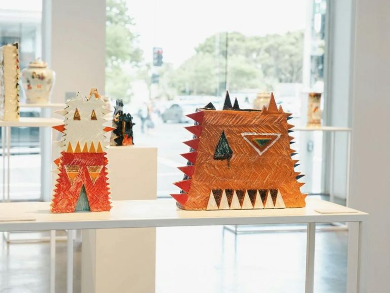 Two geometric sculptures made of clay displayed on a plinth