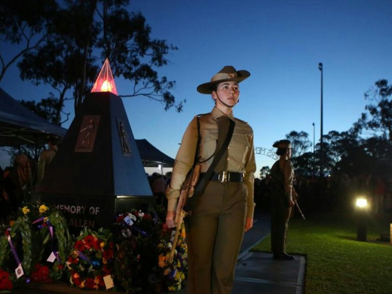 An image of a female soldier next to a cenotaph