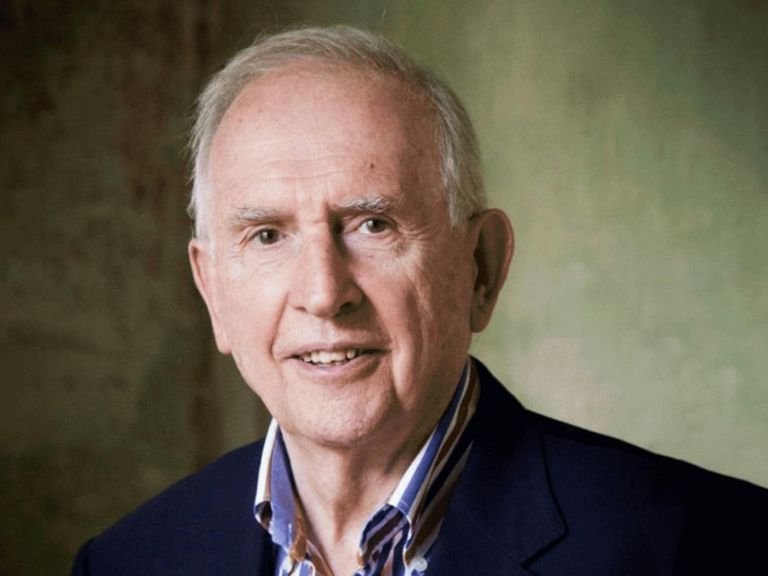 Man with grey hair slightly smiling in collared shirt and suit jacket looking directly at the viewer