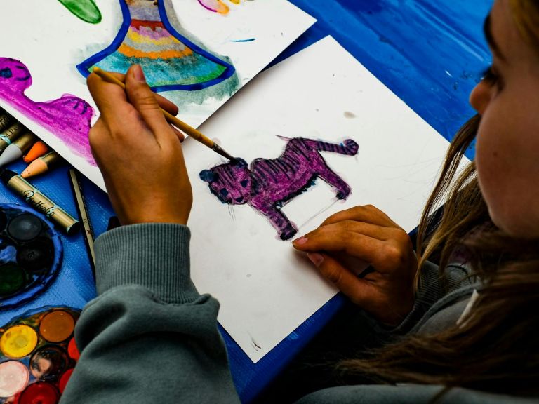 Young child with long hair drawing a purple tiger