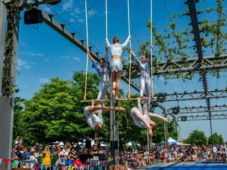 5 aerialists in silver costumes perform on a triple trapeze.