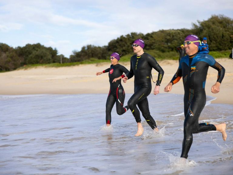 Swimmers running into the ocean