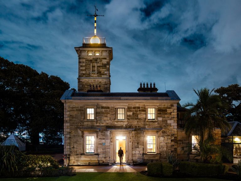 figure standing in front of illuminated sandstone building