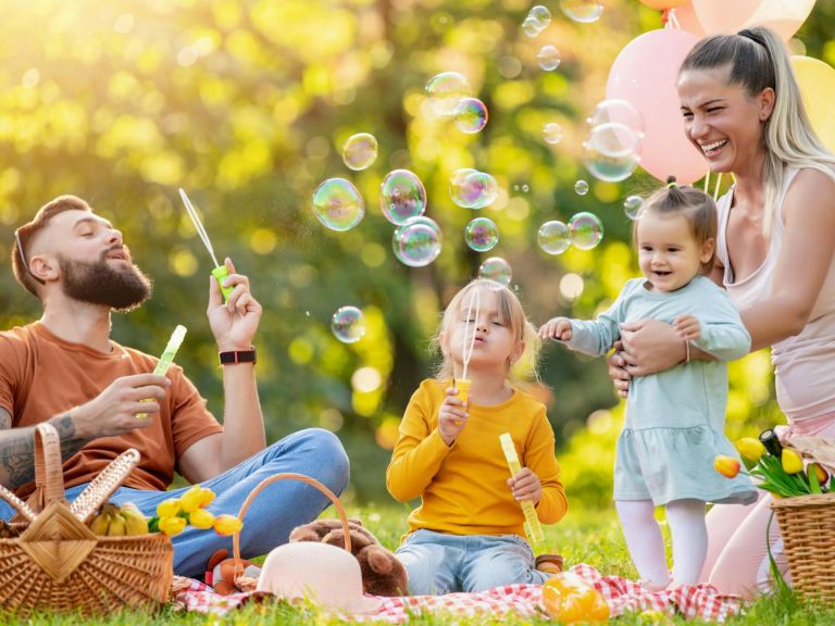 A family blowing bubbles together while having a picnic.