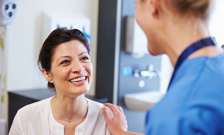 Doctor at vaccination clinic assuring a patient in her 40s