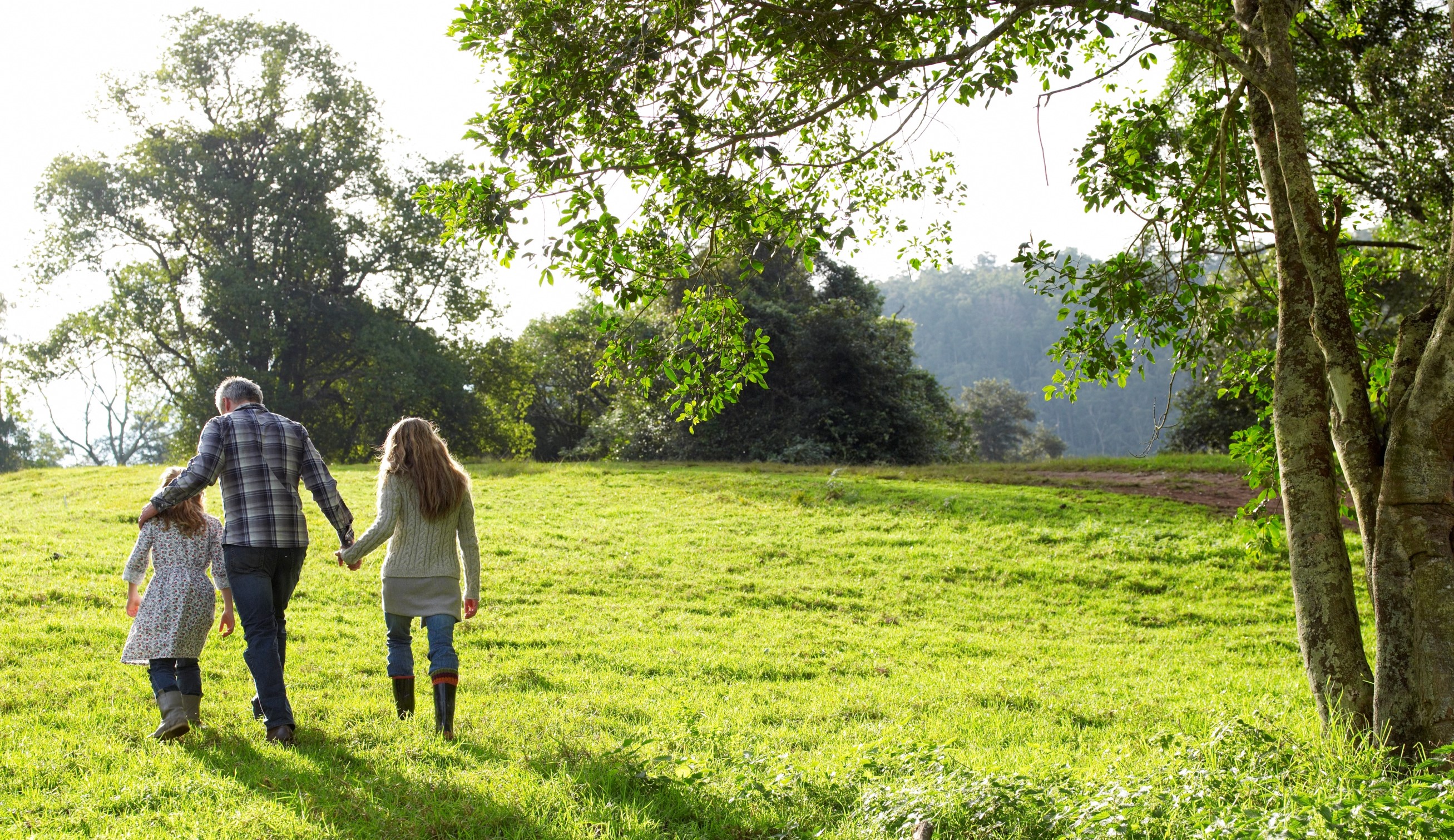 Family walking up a grassy hill together