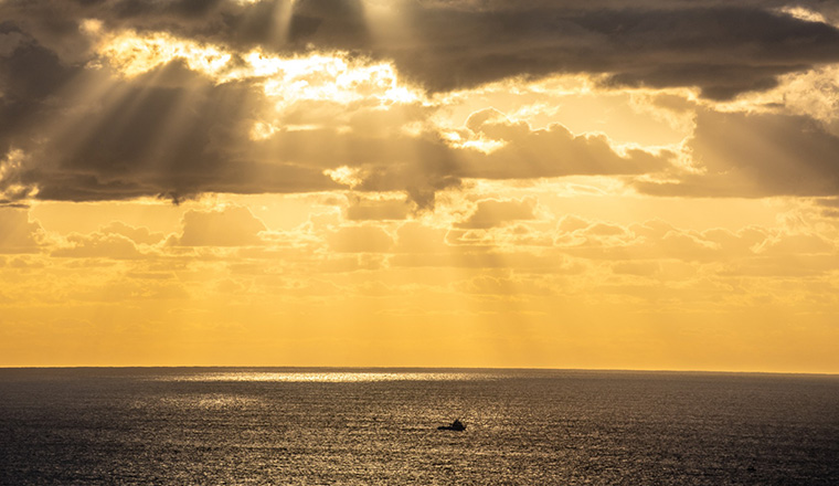 Fishing trawler in the ocean with a orange sky